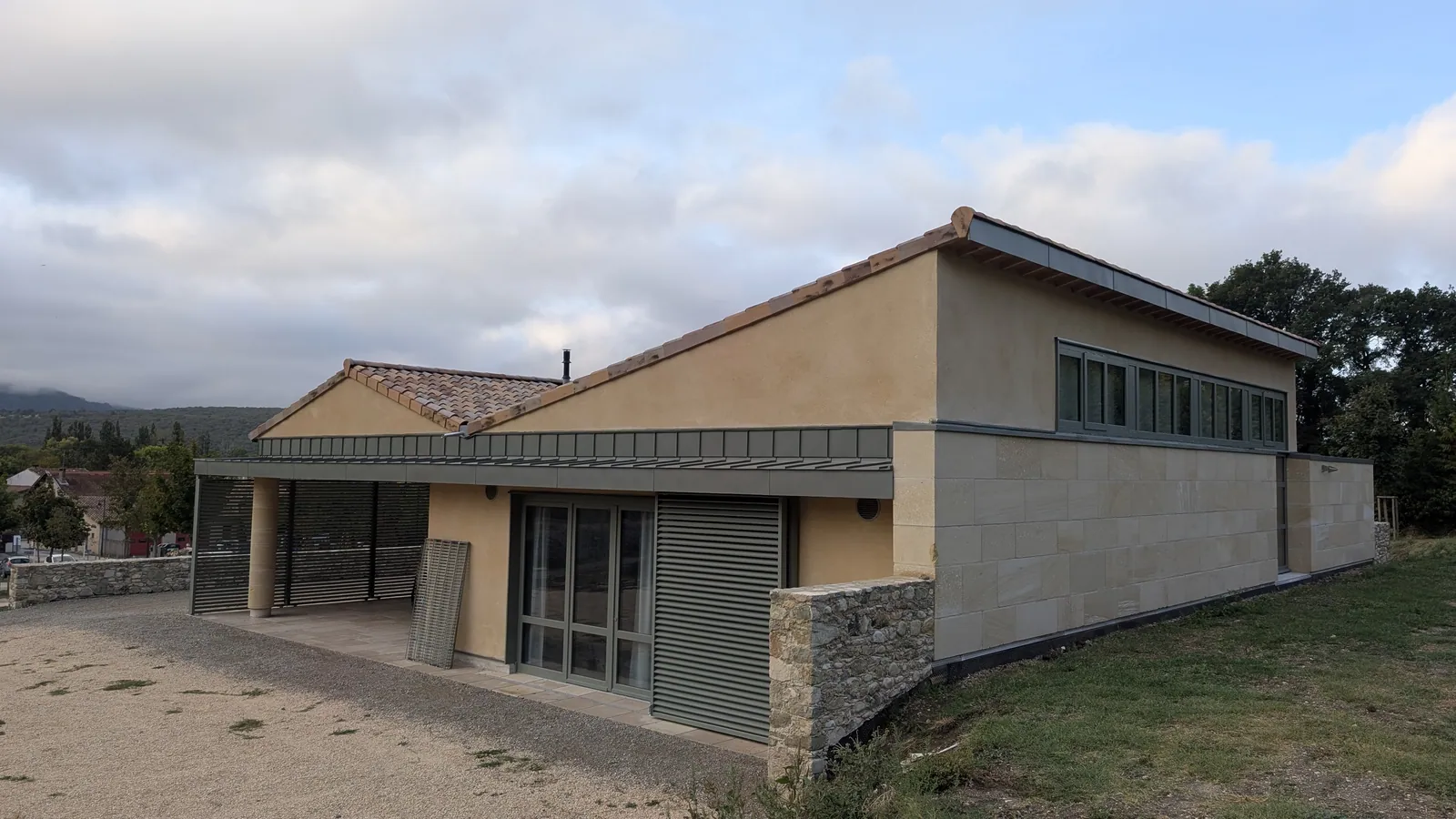 Salle multiactivités de Saoû : façade en pierre massive et auvent